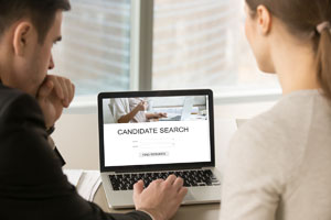 two people looking at a laptop screen.  Candidate search on the screen
